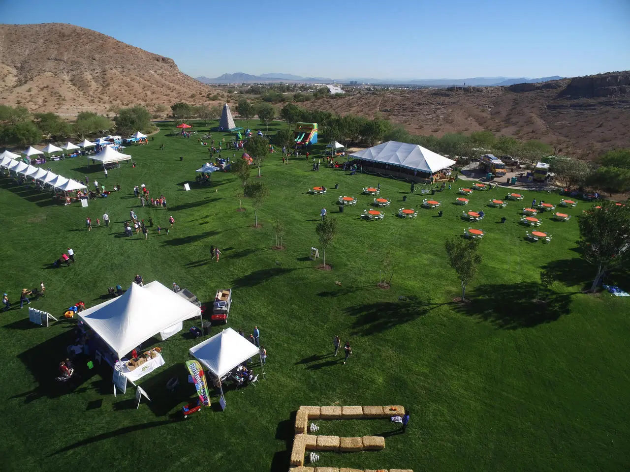 Aerial view of outdoor company picnic with orange tables, inflatables, and tents in Las Vegas