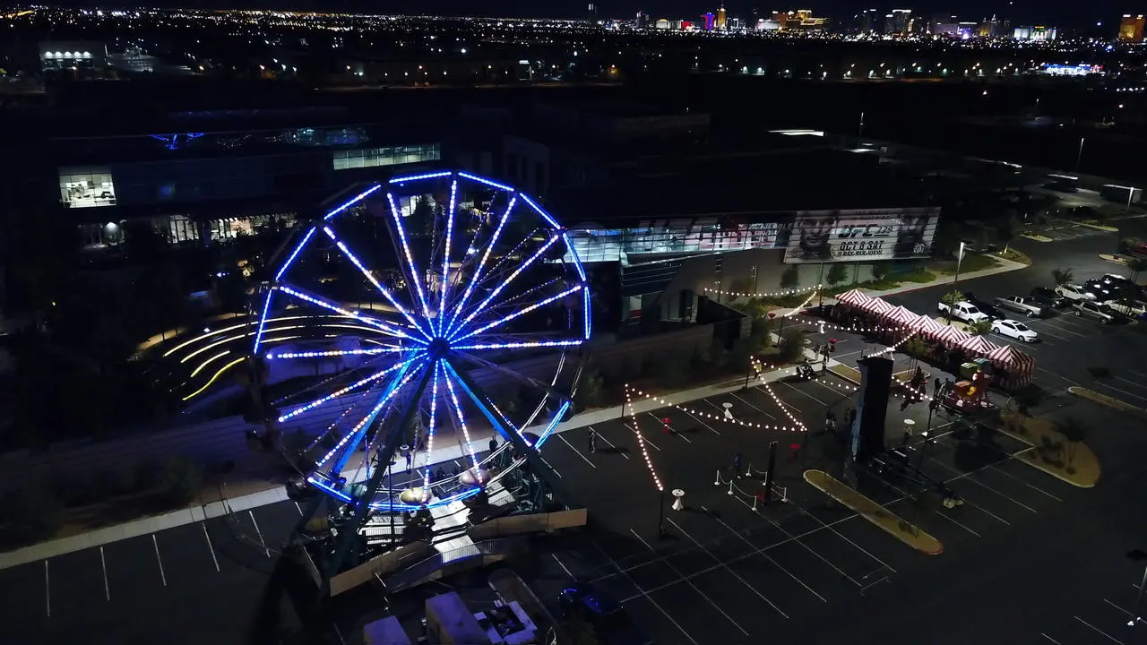Aerial Night View of Event Production with Ferris Wheel, Tents, and Las Vegas City Skyline
